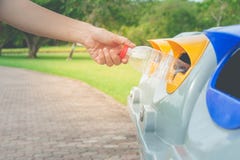 Mano de la mujer que pone la botella plástica usada en papeleras de reciclaje públicas o cubos de la basura segregados en parque fotos de archivo Mano de la mujer que pone la botella plástica usada en papeleras de reciclaje públicas o cubos de la basura segregados en parque fotos de archivo