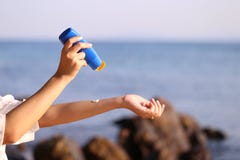 Mano de la mujer que sostiene la protecci?n solar en la playa con el mar en fondo del cielo azul, la protecci?n del sunblock del fotos de archivo libres de regalías Mano de la mujer que sostiene la protecci?n solar en la playa con el mar en fondo del cielo azul, la protecci?n del sunblock del fotos de archivo libres de regalías