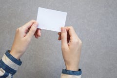 mano de la mujer que sostiene la tarjeta en blanco en fondo gris foto de archivo libre de regalías mano de la mujer que sostiene la tarjeta en blanco en fondo gris foto de archivo libre de regalías