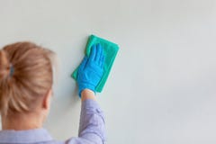 Mano degli impiegati in guanto protettivo di gomma blu che pulisce parete da polvere con lo straccio asciutto Società di pulizia fotografie stock Mano degli impiegati in guanto protettivo di gomma blu che pulisce parete da polvere con lo straccio asciutto Società di pulizia fotografie stock