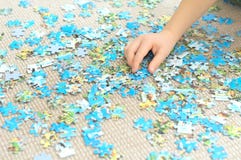 Mano del bambino che gioca puzzle complesso immagine stock libera da diritti Mano del bambino che gioca puzzle complesso immagine stock libera da diritti
