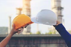 Mano del ingeniero del equipo que sostiene el casco de la seguridad en fondo de la refinería de petróleo imágenes de archivo libres de regalías Mano del ingeniero del equipo que sostiene el casco de la seguridad en fondo de la refinería de petróleo imágenes de archivo libres de regalías