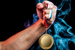 Mano dell'uomo che tiene una medaglia d'oro fotografie stock libere da diritti Mano dell'uomo che tiene una medaglia d'oro fotografie stock libere da diritti