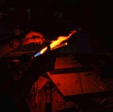 Mano di un vetro di lavoro del ventilatore di vetro sopra una fiamma aperta immagine stock libera da diritti Mano di un vetro di lavoro del ventilatore di vetro sopra una fiamma aperta immagine stock libera da diritti