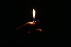 Mano femminile che tiene una fiamma più leggera contro un fondo scuro fotografia stock libera da diritti Mano femminile che tiene una fiamma più leggera contro un fondo scuro fotografia stock libera da diritti