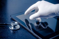 Mano in guanto medico che tocca il pc digitale moderno della compressa vicino allo stetoscopio fotografie stock Mano in guanto medico che tocca il pc digitale moderno della compressa vicino allo stetoscopio fotografie stock