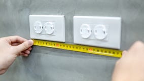 Mano maschio facendo uso della misura di nastro su sbocco elettrico fotografie stock libere da diritti Mano maschio facendo uso della misura di nastro su sbocco elettrico fotografie stock libere da diritti