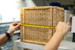 Mano maschio facendo uso della misura di nastro sulla scatola tessuta di legno immagine stock libera da diritti Mano maschio facendo uso della misura di nastro sulla scatola tessuta di legno immagine stock libera da diritti
