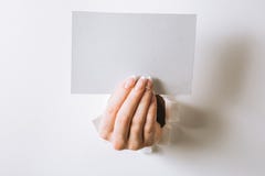Manos con una tarjeta de visita que perfora un agujero en un fondo blanco foto de archivo libre de regalías Manos con una tarjeta de visita que perfora un agujero en un fondo blanco foto de archivo libre de regalías