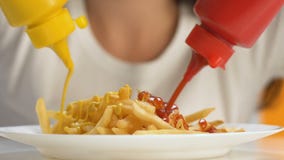 Manos femeninas que vierten la salsa de tomate y la mostaza en las patatas fritas, comida adicional de la caloría almacen de metraje de vídeo Manos femeninas que vierten la salsa de tomate y la mostaza en las patatas fritas, comida adicional de la caloría almacen de metraje de vídeo