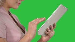 Manos femeninas usando la tableta en una pantalla verde, llave de la croma Manos femeninas usando la tableta en una pantalla verde, llave de la croma