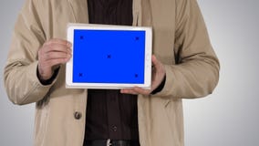 Manos masculinas que sostienen la tableta con la maqueta de la pantalla azul en fondo de la pendiente fotografía de archivo Manos masculinas que sostienen la tableta con la maqueta de la pantalla azul en fondo de la pendiente fotografía de archivo