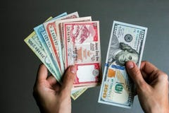 Manos que llevan a cabo moneda nepalesa y americana Manos que llevan a cabo moneda nepalesa y americana
