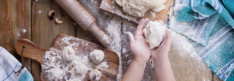 Manos y pasta del ` s de los niños con la harina en una tabla de madera y una toalla, un rodillo y un tablero verdes fotos de archivo Manos y pasta del ` s de los niños con la harina en una tabla de madera y una toalla, un rodillo y un tablero verdes fotos de archivo