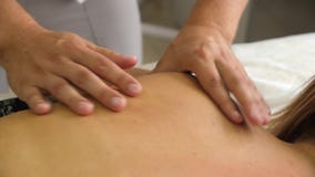 Manueller Therapeut, der eine junge Frau liegt auf einer Massagetabelle, drückend auf die Rückseite massiert Männliches Masseurha stock video footage Manueller Therapeut, der eine junge Frau liegt auf einer Massagetabelle, drückend auf die Rückseite massiert Männliches Masseurha stock video footage