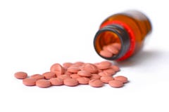 Many light pink medical pills spilling from a glass bottle container on white background royalty free stock images Many light pink medical pills spilling from a glass bottle container on white background royalty free stock images