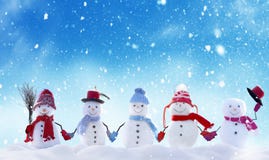 Many snowmen standing in winter Christmas landscape.