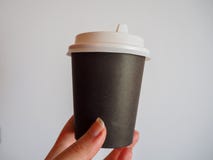 Maqueta de la mano femenina que sostiene una taza para llevar del papel del café en fondo gris con el espacio de la copia imagen de archivo Maqueta de la mano femenina que sostiene una taza para llevar del papel del café en fondo gris con el espacio de la copia imagen de archivo