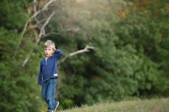 Marche blonde de garçon seule et triste dans les bois photo libre de droits Marche blonde de garçon seule et triste dans les bois photo libre de droits