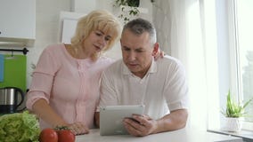 Marido mayor de explicación de la mujer madura cómo utilizar la tableta almacen de metraje de vídeo Marido mayor de explicación de la mujer madura cómo utilizar la tableta almacen de metraje de vídeo