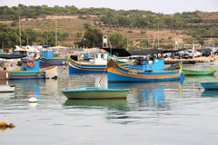 Marsaxlokk, Мальта, август 2016 Многочисленные пестротканые рыбацкие лодки в гавани города стоковые фото Marsaxlokk, Мальта, август 2016 Многочисленные пестротканые рыбацкие лодки в гавани города стоковые фото