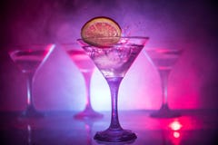 Martini cocktail glass in hand splashing on dark toned smoky background or colorful cocktail in glass with splashes and olives. royalty free stock photo Martini cocktail glass in hand splashing on dark toned smoky background or colorful cocktail in glass with splashes and olives. royalty free stock photo