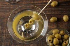 Martini i en exponeringsglasvinglas med gröna oliv på en steknål på en brun trätabell coctailar stång royaltyfria foton Martini i en exponeringsglasvinglas med gröna oliv på en steknål på en brun trätabell coctailar stång royaltyfria foton