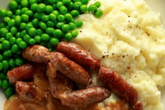 Mashed potatoes and sausages, bangers with onions gravy, green peas. close up stock photography Mashed potatoes and sausages, bangers with onions gravy, green peas. close up stock photography