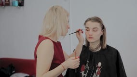 Maskenbildner wendet Berufsmake-up an einem schönen jungen Mädchen an Neues Konzept im Make-up stock footage Maskenbildner wendet Berufsmake-up an einem schönen jungen Mädchen an Neues Konzept im Make-up stock footage