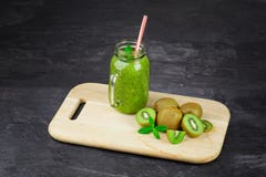 A mason jar filled with kiwi beverage, leaves of mint on a light wooden board on a dark stone background. Copy space. stock photography A mason jar filled with kiwi beverage, leaves of mint on a light wooden board on a dark stone background. Copy space. stock photography