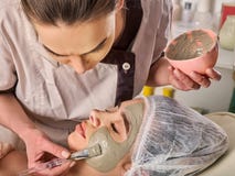Masque facial de boue de femme dans le salon de station thermale Massage de visage photographie stock libre de droits Masque facial de boue de femme dans le salon de station thermale Massage de visage photographie stock libre de droits