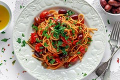 Massa italiana Alla Puttanesca do vegetariano com alho, azeitonas, alcaparras com na placa branca imagem de stock Massa italiana Alla Puttanesca do vegetariano com alho, azeitonas, alcaparras com na placa branca imagem de stock