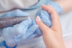 Master of manicure in rubber gloves makes a manicure with the help of a nail polish machine on the nails of a woman Royalty Free Stock Images Master of manicure in rubber gloves makes a manicure with the help of a nail polish machine on the nails of a woman Royalty Free Stock Images