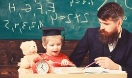 Matematikkursbegrepp Fadern undervisar sonmatematik L?rare i formella kl?der och elev i akademikerm?ssa i klassrum royaltyfri foto Matematikkursbegrepp Fadern undervisar sonmatematik L?rare i formella kl?der och elev i akademikerm?ssa i klassrum royaltyfri foto
