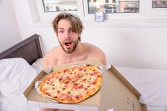 Mathemsändning Man den skäggiga stiliga grabben som äter ostliknande mat för frukost i säng Mannen gillar pizza för frukost arkivfoto Mathemsändning Man den skäggiga stiliga grabben som äter ostliknande mat för frukost i säng Mannen gillar pizza för frukost arkivfoto