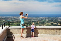 Matka z córką przy San Marino obserwaci pokładem Mama bierze krajobrazową fotografię z smartphone Dziecko patrzeje włocha wybrzeż fotografia stock Matka z córką przy San Marino obserwaci pokładem Mama bierze krajobrazową fotografię z smartphone Dziecko patrzeje włocha wybrzeż fotografia stock