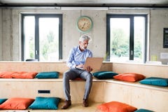 Mature businessman with laptop in creative office. stock image Mature businessman with laptop in creative office. stock image