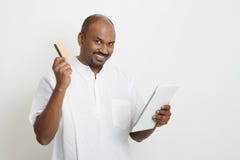 Mature casual business Indian man using tablet pc and credit car stock photography Mature casual business Indian man using tablet pc and credit car stock photography