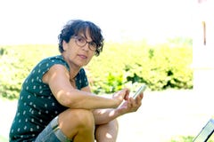 Woman sitting on the deck chair in garden using smartphone Royalty Free Stock Photos Woman sitting on the deck chair in garden using smartphone Royalty Free Stock Photos