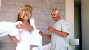 Mature couple having a pillow fight and laughing