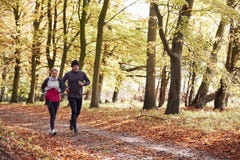 Mature Couple Running Through Autumn Woodland Together stock photo Mature Couple Running Through Autumn Woodland Together stock photo