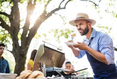 A mature man with family and friends cooking and serving food on a barbecue party. stock image A mature man with family and friends cooking and serving food on a barbecue party. stock image