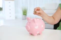 Mature woman putting money into piggy bank at table, closeup. royalty free stock images Mature woman putting money into piggy bank at table, closeup. royalty free stock images