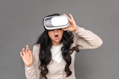 Freestyle. Mature lady in virtual reality headset standing isolated on grey playing surprised stock image Freestyle. Mature lady in virtual reality headset standing isolated on grey playing surprised stock image