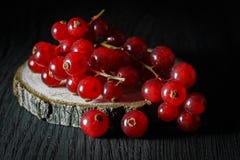 Mazzo maturo di ribes rosso su un taglio di un albero, fondo scuro fotografia stock libera da diritti Mazzo maturo di ribes rosso su un taglio di un albero, fondo scuro fotografia stock libera da diritti