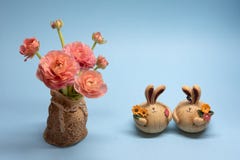 Mazzo sveglio dei ranuncoli e delle figurine rosa delicati della lepre su un fondo blu fotografie stock libere da diritti Mazzo sveglio dei ranuncoli e delle figurine rosa delicati della lepre su un fondo blu fotografie stock libere da diritti