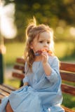 Mała dziewczynka model w błękita słońca i sukni szkłach siedzi na ławce w parku obrazy royalty free Mała dziewczynka model w błękita słońca i sukni szkłach siedzi na ławce w parku obrazy royalty free