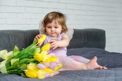 Mała dziewczynka z tulipanami w czarodziejek ubraniach siedzi na łóżku 9 trybowi stubarwni obrazki ustawiających wiosna tulipanów zdjęcie stock Mała dziewczynka z tulipanami w czarodziejek ubraniach siedzi na łóżku 9 trybowi stubarwni obrazki ustawiających wiosna tulipanów zdjęcie stock
