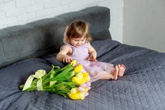 Mała dziewczynka z tulipanami w czarodziejek ubraniach siedzi na łóżku 9 trybowi stubarwni obrazki ustawiających wiosna tulipanów zdjęcia royalty free Mała dziewczynka z tulipanami w czarodziejek ubraniach siedzi na łóżku 9 trybowi stubarwni obrazki ustawiających wiosna tulipanów zdjęcia royalty free