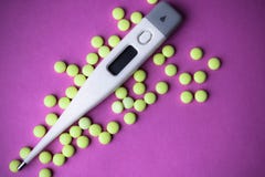 Małe medyczne pharmacetic round pigułki, witaminy, leki i elektroniczny cyfrowy termometr na różowym purpurowym tle, obrazy royalty free Małe medyczne pharmacetic round pigułki, witaminy, leki i elektroniczny cyfrowy termometr na różowym purpurowym tle, obrazy royalty free